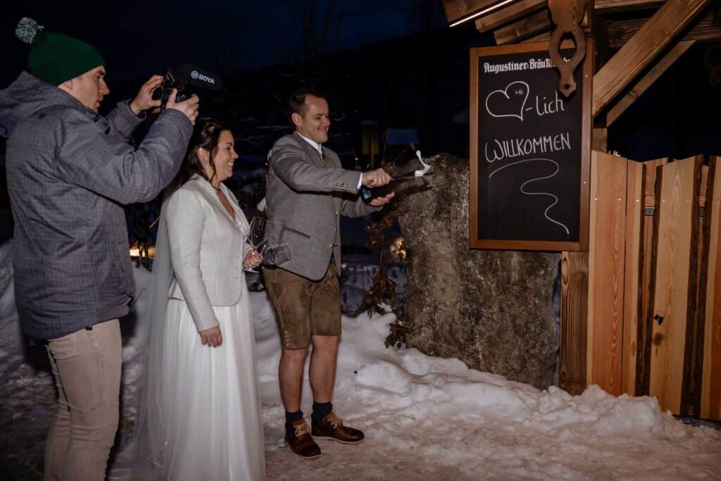 Videograaf filmt bruidspaar in de sneeuw terwijl champagne met een sabel wordt geopend